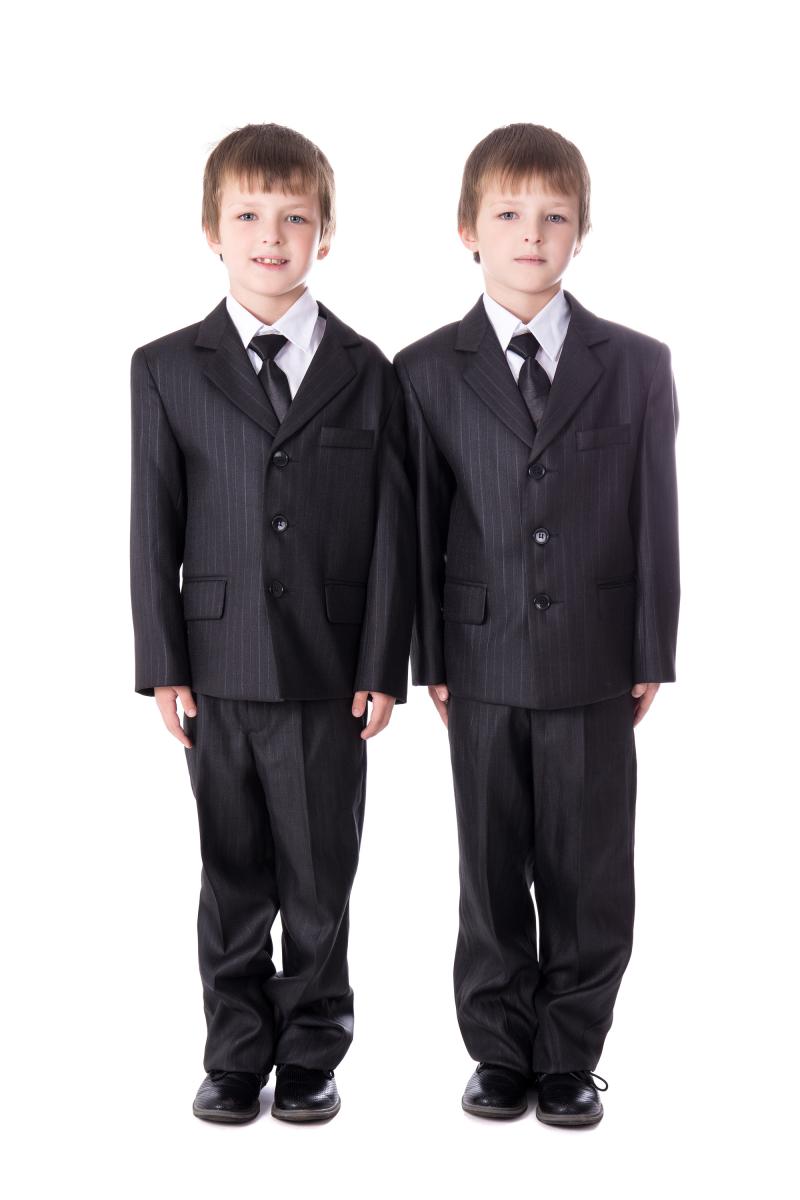 A picture of two boys wearing suits and ties and looking angelic.